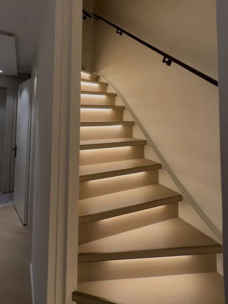 Lichte trap met verlichting onder de treden en zwarte leuning